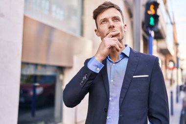 Young man business worker standing with doubt expression at street