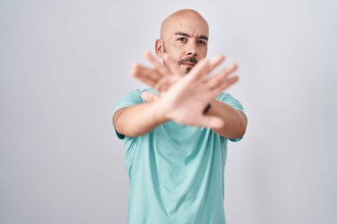 Middle age bald man standing over white background rejection expression crossing arms and palms doing negative sign, angry face 
