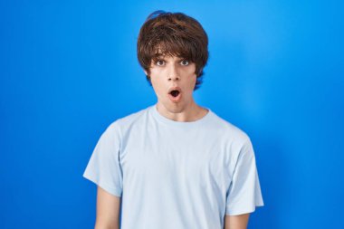 Mavi arka planda duran İspanyol genç adam şaşkınlık ve şaşkınlık dolu bir ifade, korku ve heyecanlı bir yüz ifadesiyle dehşete düşmüş ve şok olmuştu.. 