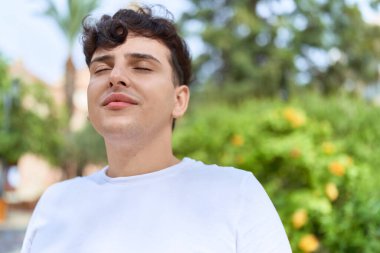 Non binary man breathing with closed eyes at park