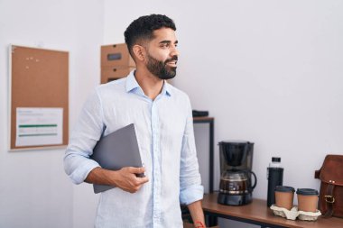 Young arab man business worker smiling confident holding laptop at office