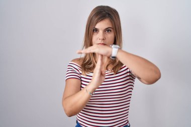 Young hispanic woman standing over isolated background doing time out gesture with hands, frustrated and serious face 