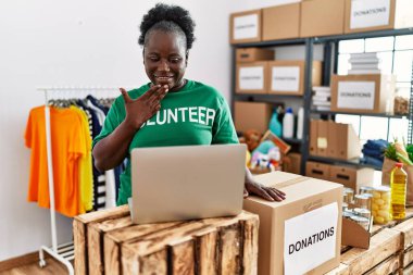 Gönüllü üniforma giyen genç Afrikalı Amerikalı kadın yardım merkezinde sağır işaret dilini kullanarak konuşuyor.