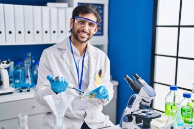 Genç İspanyol bilim adamı laboratuarda çalışırken gülümsüyor.