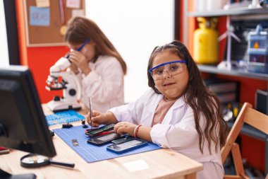 Two kids students using microscope repairing smartphone at laboratory classroom