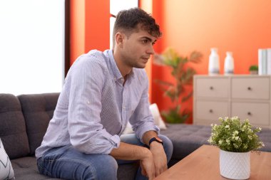 Young hispanic man stressed sitting on sofa at home