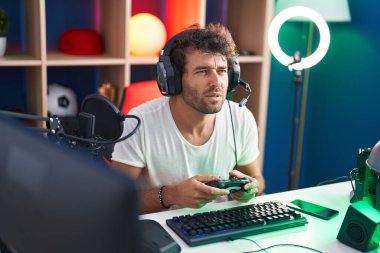 Genç İspanyol asıllı adam müzik stüdyosunda joystick kullanarak video oyunu oynuyor.