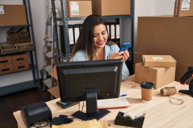 Young beautiful plus size woman ecommerce business worker using smartphone at office