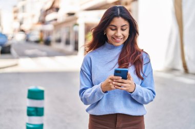 Sokakta akıllı telefon kullanan, kendine güvenen genç İspanyol kadın.