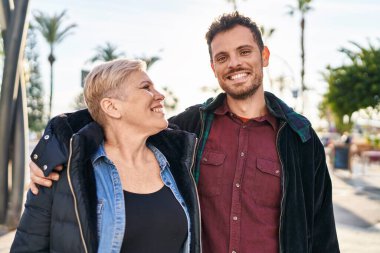 Mother and son smiling confident hugging each other at street