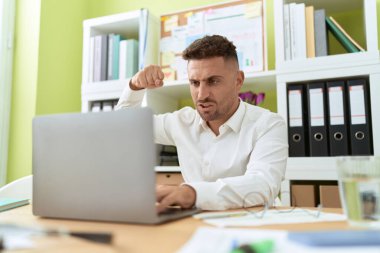 Young hispanic man business worker angry screaming at office