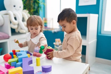 Anaokulunda inşaat bloklarıyla oynayan iki çocuk.