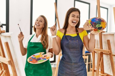Anne ve kızı resim stüdyosunda kendine güvenen bir şekilde gülümsüyor.