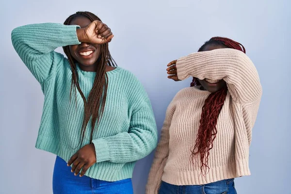 Две Африканки Стоящие Синем Фоне Закрывая Глаза Улыбаясь Веселыми Смешными — стоковое фото