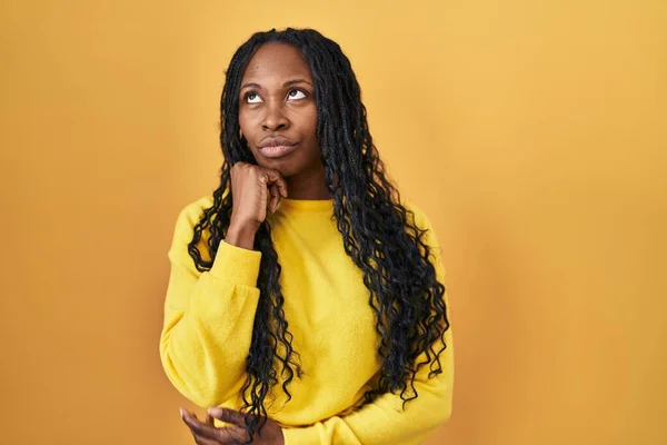 African Woman Standing Yellow Background Hand Chin Thinking Question Pensive — Stockfoto