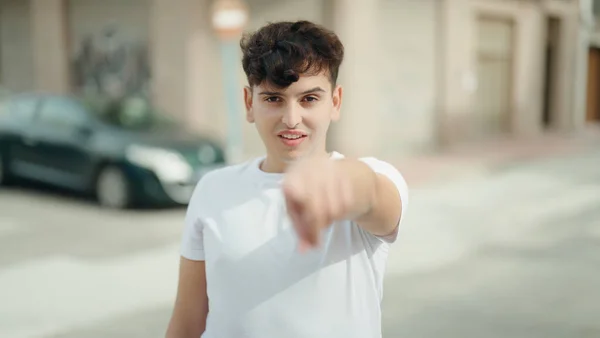 Non binary man smiling confident pointing with finger at street