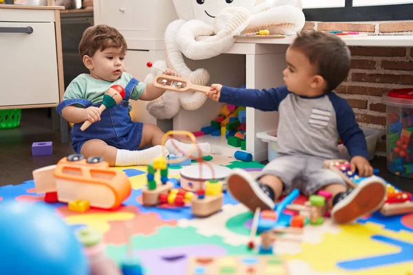 木琴とマラッカを演奏する2人の子供が幼稚園で床に座っています — ストック写真