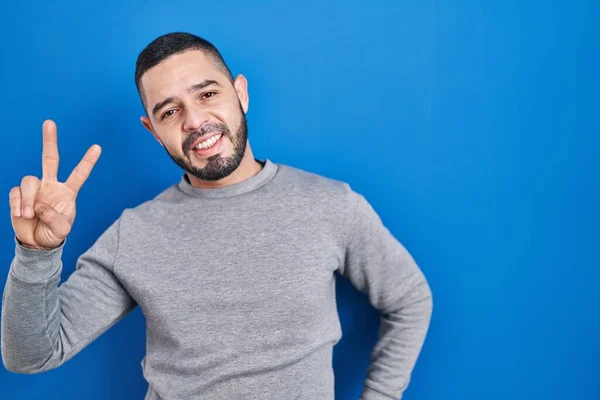 Hispanic Man Standing Blue Background Smiling Looking Camera Showing Fingers —  Fotos de Stock