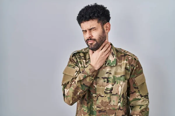 Arab man wearing camouflage army uniform touching painful neck, sore throat for flu, clod and infection