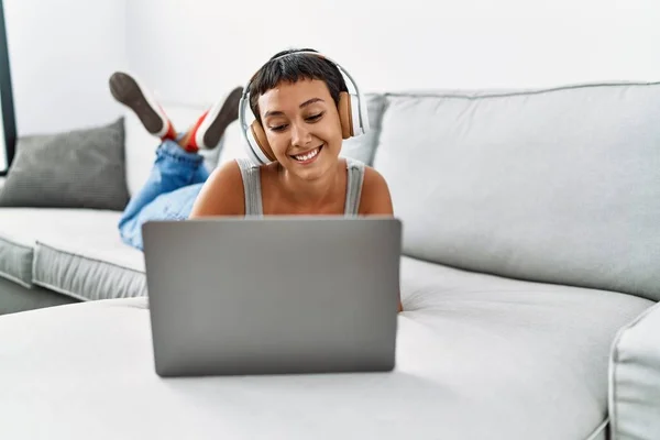 Genç Spanyol Kadın Evdeki Kanepede Dizüstü Bilgisayar Kullanarak Müzik Dinliyor — Stok fotoğraf