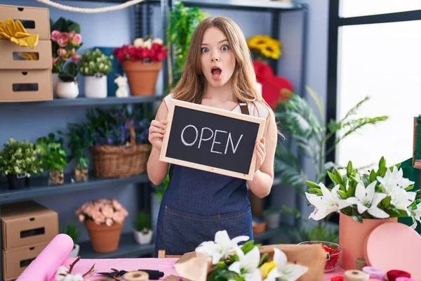 Caucasian woman working at florist holding open sign afraid and shocked with surprise and amazed expression, fear and excited face.