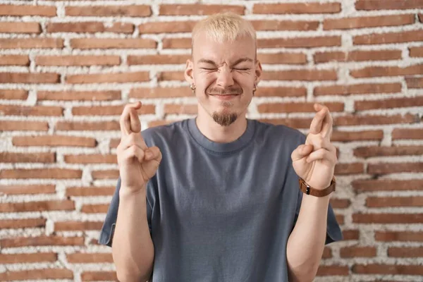 Young Caucasian Man Standing Bricks Wall Gesturing Finger Crossed Smiling — Photo