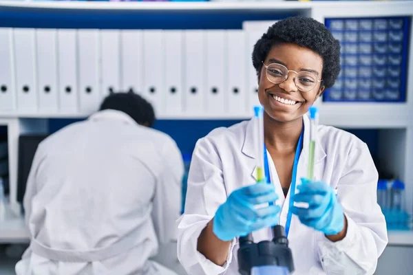 アフリカ系アメリカ人の男性と女性科学者が実験室で試験管を持っている — ストック写真