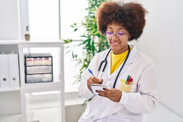 Afroamerikanerin Trägt Arztuniform Und Schreibt Klinik Auf Notizbuch — Stockfoto
