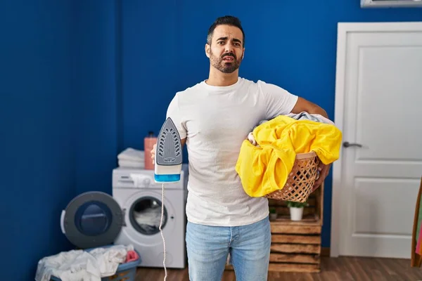 Young Hispanic Man Beard Holding Iron Clothes Home Clueless Confused — Stockfoto
