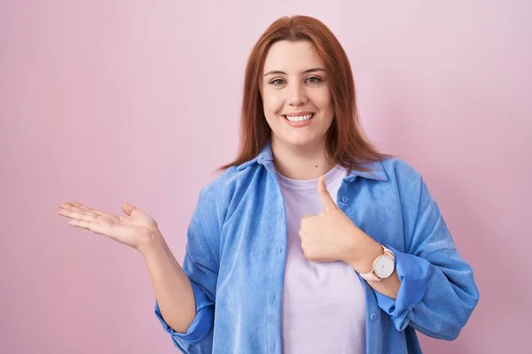 Young Hispanic Woman Red Hair Standing Pink Background Showing Palm —  Fotos de Stock