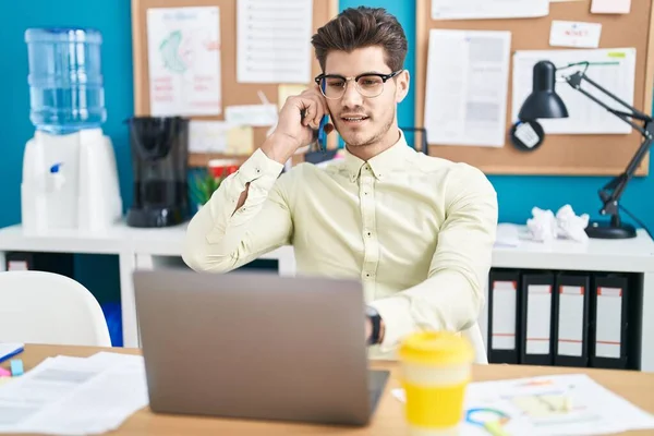 Young Hispanic Man Business Worker Using Laptop Talking Smartphone Office — Stock fotografie