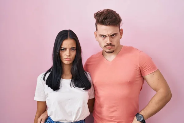 Young Hispanic Couple Standing Pink Background Skeptic Nervous Frowning Upset — Zdjęcie stockowe