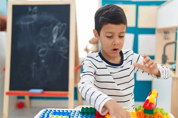 幼稚園でテーブルの上に座っている建設ブロックと遊んで愛らしいヒスパニック系の男の子 — ストック写真