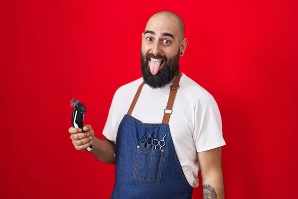 Mladý Hispánec Vousy Tetováním Holičské Zástěře Držící Žiletku Vystrkující Jazyk — Stock fotografie