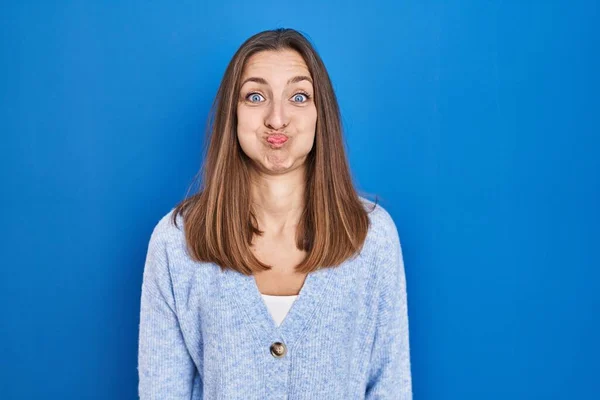 Young Woman Standing Blue Background Puffing Cheeks Funny Face Mouth — 图库照片