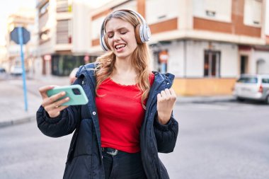 Sokakta video oyunu oynarken kendine güvenen genç sarışın kadın.