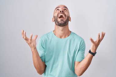 Middle age bald man standing over white background celebrating mad and crazy for success with arms raised and closed eyes screaming excited. winner concept 