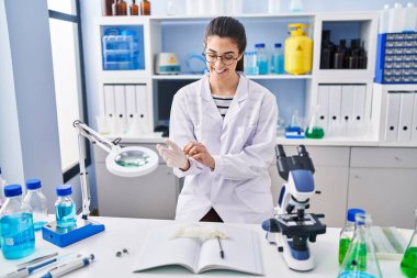 Genç ve güzel İspanyol bilim adamı. Laboratuvarda eldiven takarak gülümsüyor.