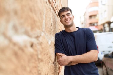 Sokakta kollarını kavuşturmuş İspanyol genç bir adam.