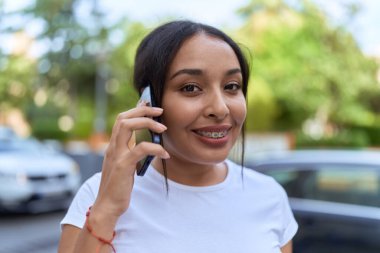 Young arab woman smiling confident using smartphone at street