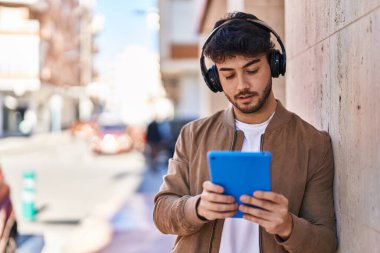 Sokakta dokunmatik ped ve kulaklık kullanan genç bir İspanyol.