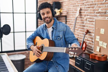 Genç Arap müzisyen müzik stüdyosunda klasik gitar çalıyor.