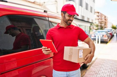 Genç İspanyol kurye sokakta dokunmatik ped paketi kullanıyor.