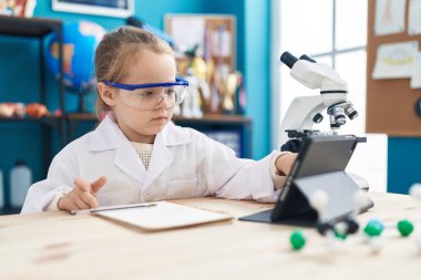 Adorable blonde girl student using touchpad at laboratory classroom
