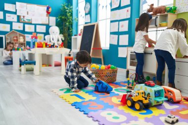 Group of kids playing with telephone toy sitting on floor at kindergarten