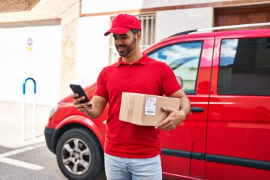 Genç İspanyol kurye sokakta akıllı telefon paketi kullanıyor.