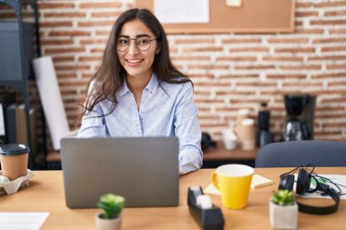 Ofiste çalışan genç İspanyol iş kadını laptopu kullanıyor.