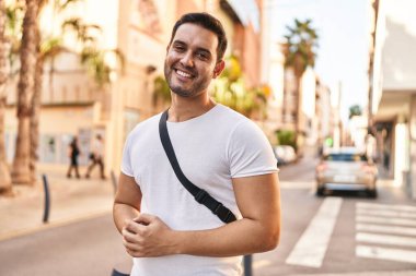 Sokakta kendinden emin gülümseyen İspanyol genç adam.