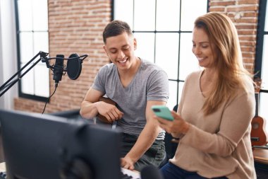 Man and woman musicians having classic guitar lesson using smartphone at music studio