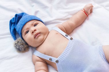 Yatak odasında yün şapka takan sevimli İspanyol bebek.